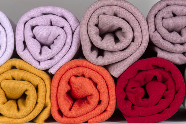 Rolls of knitted fabric in different shades, purple, white, red, close-up - Φωτογραφία, εικόνα