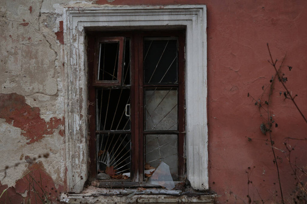 A window with broken glass in the wall of an abandoned house - Φωτογραφία, εικόνα