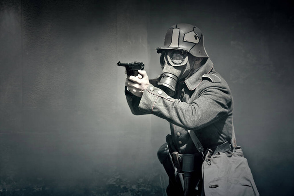 Żołnierz II Wojny Światowej w masce gazowej celuje w broń. Koncepcja wojny.  - Zdjęcie, obraz