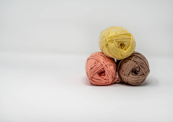 Three balls of colourful woolen yarn on a plain white background with copy space. - Фото, изображение