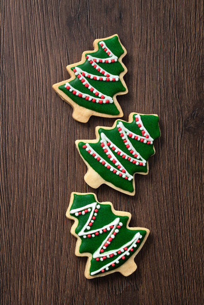 Top view of decorated green plain flavor gingerbread Christmas tree cookie on wooden table background with copy space, concept of holiday celebration. - Valokuva, kuva