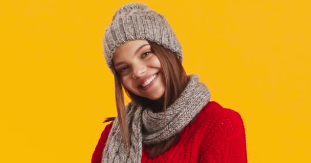 Studio muotokuva hymyilevä nainen neulottu hattu ja huivi, poseeraa keltainen tausta - Materiaali, video