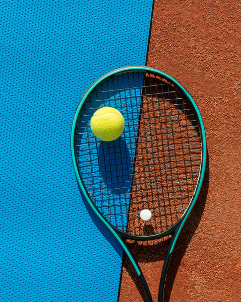 raqueta de tenis y pelotas en pista de arcilla roja y alfombra de gimnasio azul. Tenis deportivo, juegos activos, ocio y estilo de vida saludable. Fondo deportivo. Vertical. Copiar espacio - Foto, Imagen