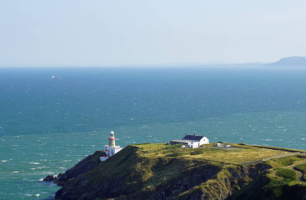 The town of Howth is located on the peninsula Howth Head directly opposite the Dublin district of Sutton and is connected to the mainland via a dam. The Baily Lighthouse stands on a promontory and is well visible from the Hill of Howth. - Photo, Image