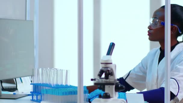 Portret czarnej kobiety chemik wpisujący na komputerze sprawdzający rozwój wirusa - Materiał filmowy, wideo