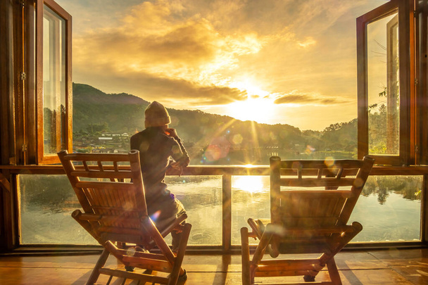 joven mujer sola viendo vista al lago en la cafetería en el amanecer de la mañana, pueblo tailandés de Ban Rak, provincia de Mae Hong Son, Tailandia. Concepto de viaje - Foto, Imagen