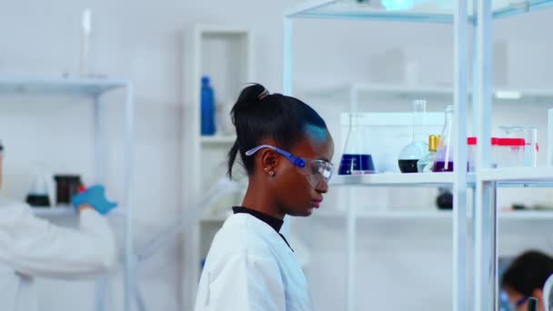 Femme chimiste africaine chercheuse utilisant des équipements en verre en laboratoire - Séquence, vidéo
