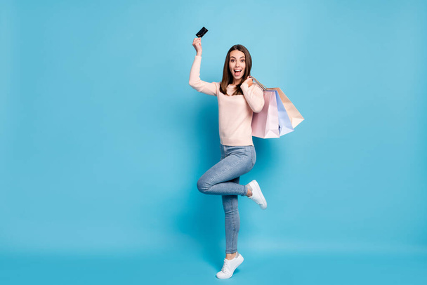 Full length body size view of nice attractive cheerful brown-haired girl jumping having fun carrying new things using credit card bargain isolated bright vivid shine vibrant blue color background - Fotoğraf, Görsel
