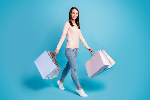 Full length body size view of her she nice attractive lovely cheerful cheery brown-haired girl walking carrying new things bargain retail isolated bright vivid shine vibrant blue color background - Фото, изображение
