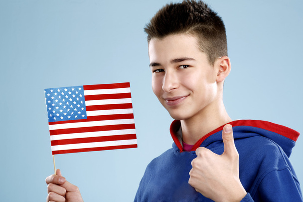 молодий усміхнений студент-підліток тримає прапор
 - Фото, зображення