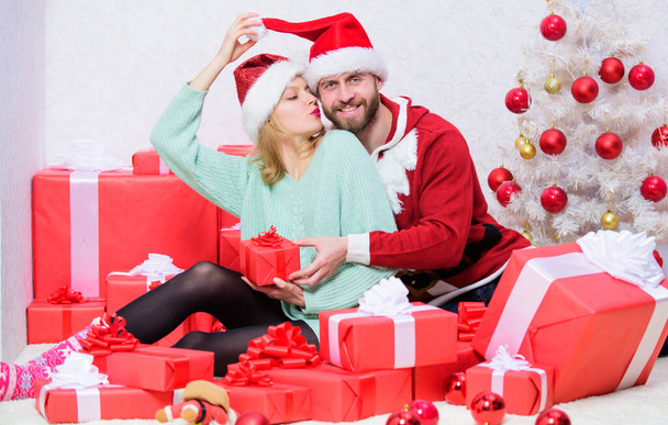 Couple in love enjoy christmas holiday celebration. Opening christmas present. Pleasant surprise. Couple sit near pile of gift boxes and christmas tree background. Husband prepared christmas surprise - Фото, зображення