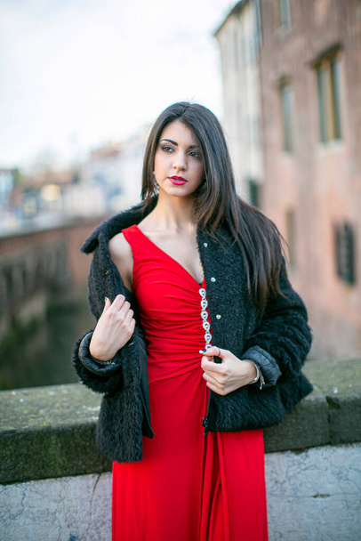 hermosa chica con el pelo largo mediterráneo negro posando con vestido largo rojo. Foto de alta calidad - Foto, Imagen