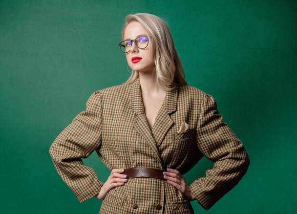 Blond vrouw in Britse stijl jas op groene achtergrond  - Foto, afbeelding