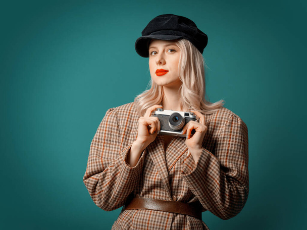 woman in British style jacket and beret with vintage camera on green background - Photo, Image