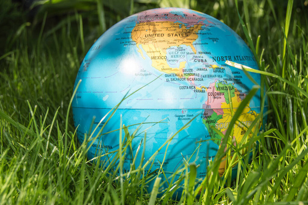 Το παγκόσμιο μοντέλο της Γης στο πράσινο γρασίδι δείχνει ECO έννοια, προστατεύοντας τον κόσμο από πανδημίες, καλοκαίρι, υπαίθρια. - Φωτογραφία, εικόνα