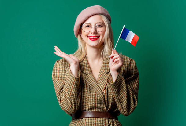 beautiful woman in style jacket and hat with French flag on green background - Photo, Image