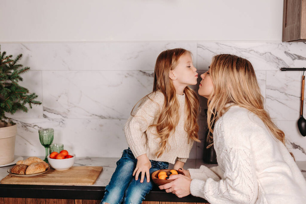 happy mother and little daughter hugging while having breakfast at home in morning - Foto, imagen