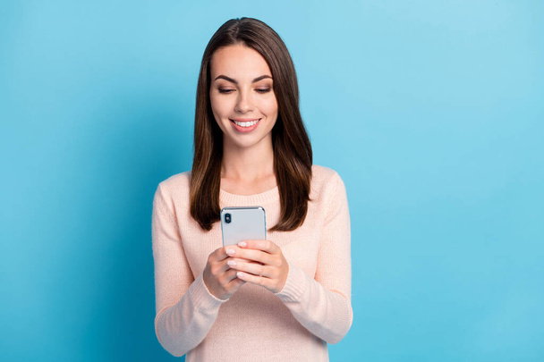 Photo of positive girl read social network feedback on smartphone wear pastel pullover isolated over blue color background - 写真・画像