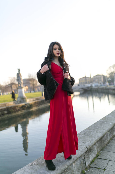 beautiful girl with long black hair standing at the edge of the canal in the square in padua. High quality photo - Photo, Image