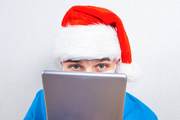 Young Man in Santa Hat with a Tablet Computer by the White Wall closeup - Foto, Imagem