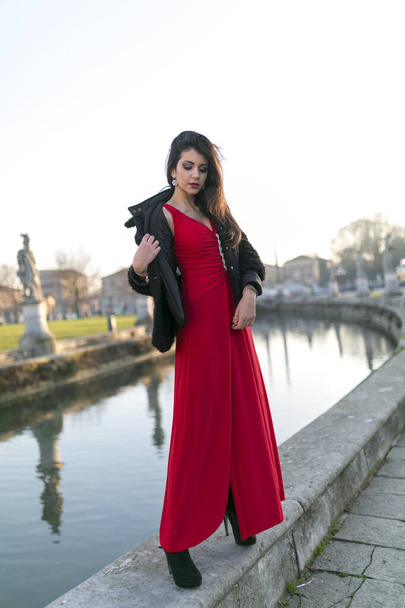 schönes Mädchen mit langen schwarzen Haaren, das am Rand des Kanals auf dem Platz in Padua steht. Hochwertiges Foto - Foto, Bild
