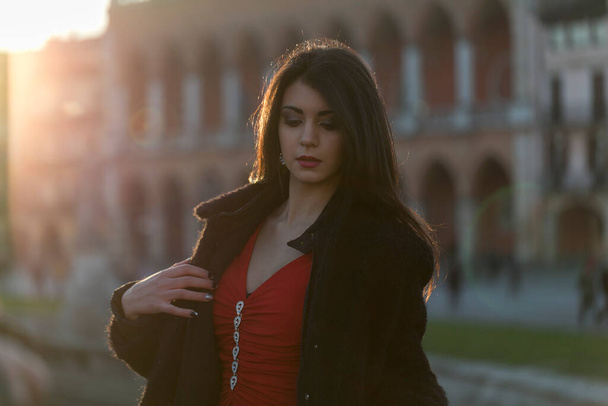 beautiful girl with long mediterranean black hair at sunset in the square of padua. High quality photo - Photo, Image