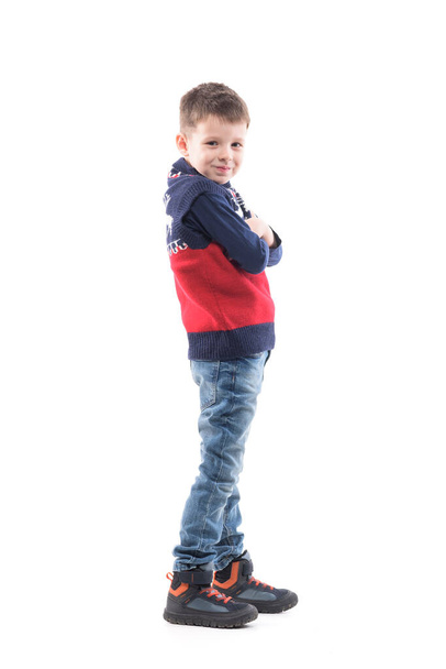 Boční pohled na cool dítě sebevědomý mladý chlapec pózuje se zkříženýma rukama dívá do kamery. Celotělový portrét izolovaný na bílém pozadí.  - Fotografie, Obrázek