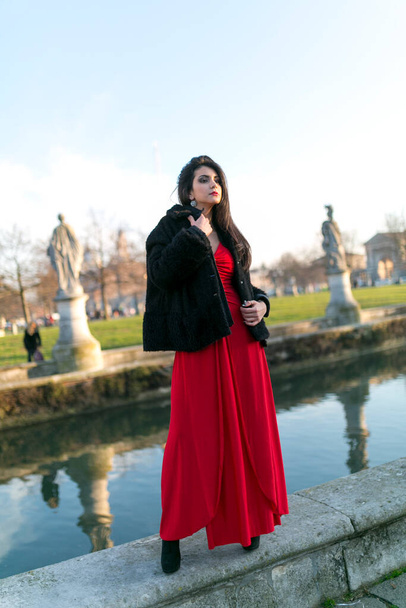 schönes Mädchen mit langen schwarzen Haaren, das am Rand des Kanals auf dem Platz in Padua steht. Hochwertiges Foto - Foto, Bild