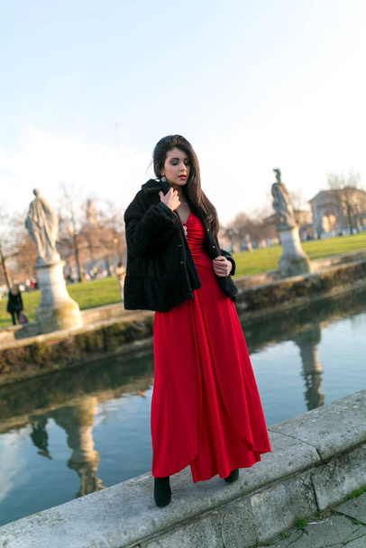 menina bonita com longos cabelos pretos de pé na borda do canal na praça em Pádua. Foto de alta qualidade - Foto, Imagem