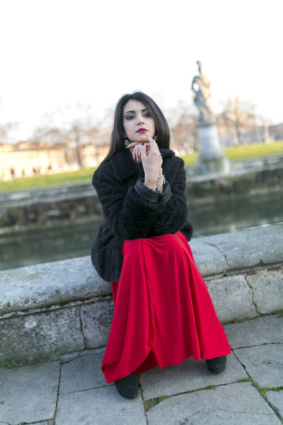 beautiful girl with long black hair at sunset sitting in the square in padua. High quality photo - Fotografie, Obrázek
