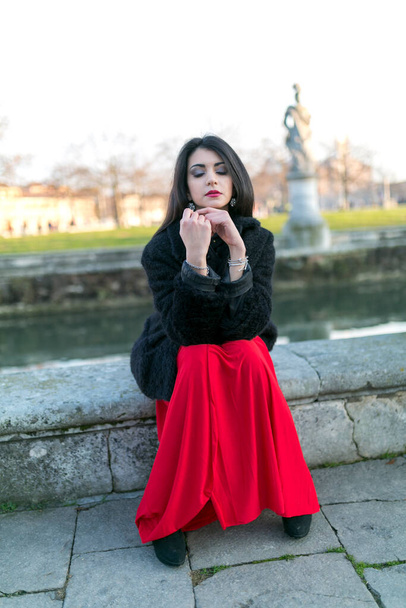 beautiful girl with long black hair at sunset sitting in the square in padua. High quality photo - Photo, Image