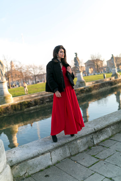 beautiful girl with long black hair standing at the edge of the canal in the square in padua. High quality photo - Photo, Image