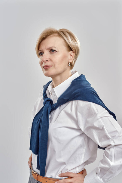 Portrait of elegant middle aged caucasian woman wearing business attire having a serious, confident look while posing isolated over grey background - Foto, immagini