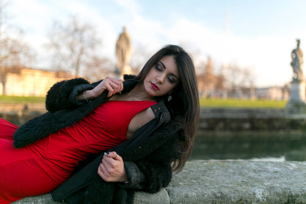 beautiful girl with long black hair at sunset lying in the square in padua. High quality photo - Photo, Image