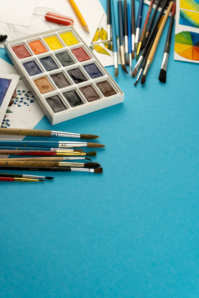 Watercolor paints and brushes. Artists workplace and desk. Color palette. Drawing blue background. Place for your text. Art created. Copy space. - Foto, Imagem