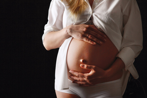 Pregnant woman touching her belly with hands - Photo, Image