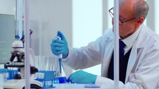 Laboratorní senior man vědec pracující s zkumavkami a pipetou - Záběry, video
