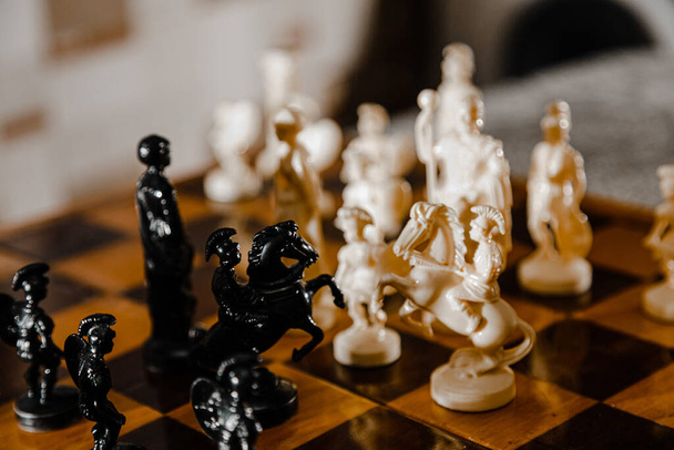 Σκάκι λευκό και μαύρα κομμάτια πολεμούν στο πεδίο της μάχης για τον βασιλιά τους. - Φωτογραφία, εικόνα