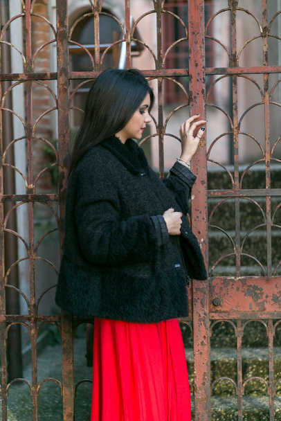 hermosa chica con el pelo largo mediterráneo negro posando con vestido largo rojo. Foto de alta calidad - Foto, imagen