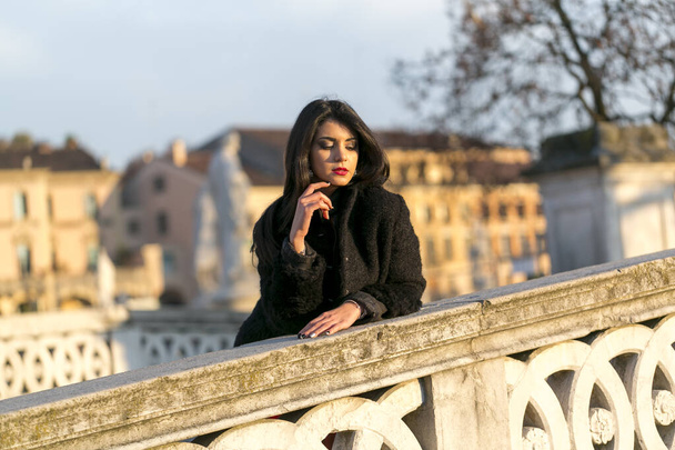 bella ragazza con lunghi capelli neri al tramonto sul ponte di Padova. Foto di alta qualità - Foto, immagini