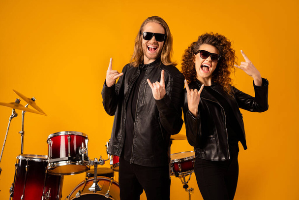 Portré vicces két ember barátnő rock banda csapat élvezze party punk esemény show szarvas szimbólum viselet fekete bőr kabát napszemüveg elszigetelt felett fényes fény háttér - Fotó, kép