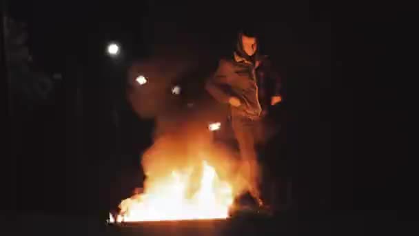 Man in spijkerjasje gaat op de weg rond een grote brand - Video