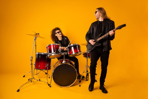 Full size photo of girlfriend boyfriend cool punk music players enjoy practice sound guitar drum solo wear leather black jacket glasses sunglass isolated over bright shine color background - 写真・画像