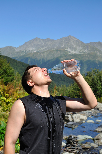 der junge Mann trinkt eifrig Wasser aus Plastikflaschen - Foto, Bild