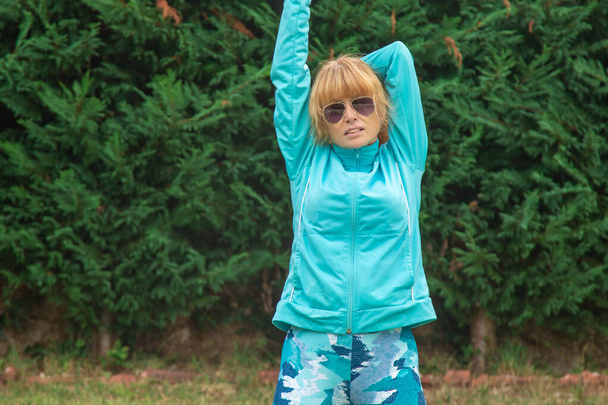 взрослый или пожилая женщина делает упражнения или спорт на открытом воздухе - Фото, изображение