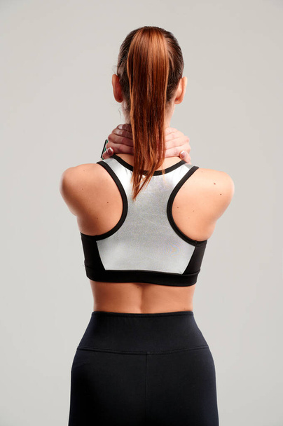 背中の背骨に痛みを示す女性の体。白い背景に首に急性痛みを感じるスポーツ女性. - 写真・画像
