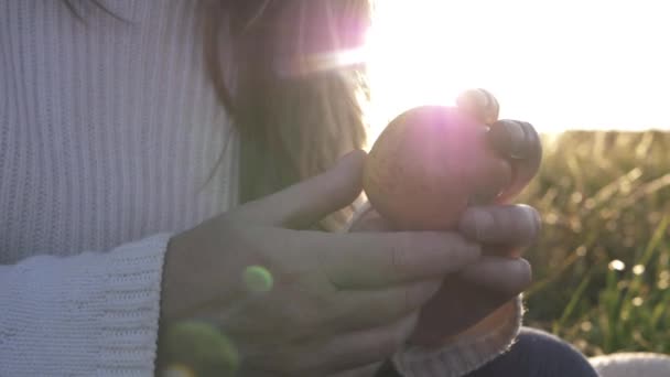 Mujer sosteniendo jugosa manzana roja contra medio iluminado por el sol de cerca disparo - Metraje, vídeo