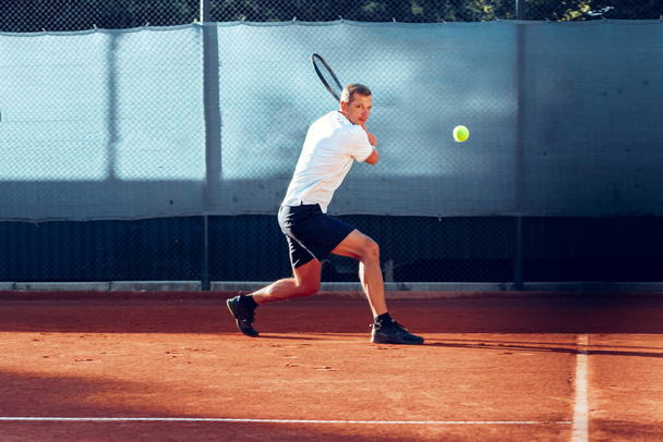Proffesional tennis player beats off a ball during match - Фото, зображення