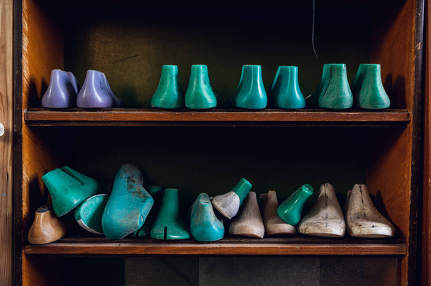 In the workshop in a wooden rack are colored blanks for different shoes - Photo, Image