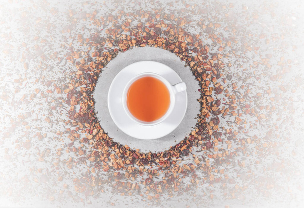 Concept of fruit tea. Mix of dried flowers petals and berries around teacup on gray table. Topview, from above - Fotó, kép
